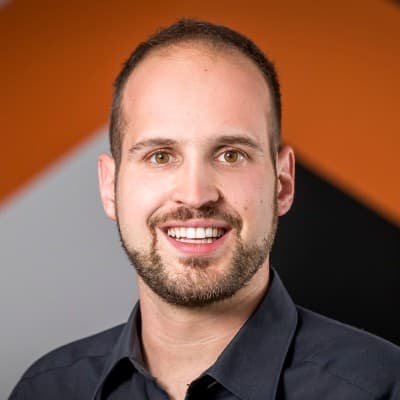 Ein Mann mit kurzen Haaren und einem Bart. Er trägt ein dunkelblaues Hemd.