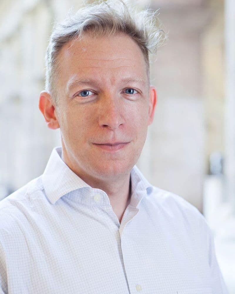 Ein Mann mit kurzen, blonden Haaren. Er trägt ein weisses Hemd.