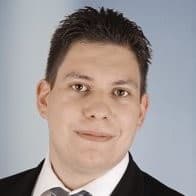 Ein Mann mit kurzen, schwarzen Haaren. Er trägt einen Anzug.